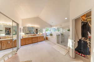 Master bath with a jetted garden tub, a shower, double vanity, vaulted ceiling, and a walk-in closet