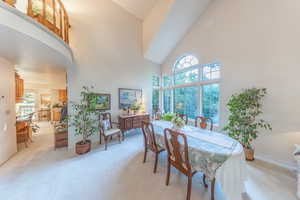 Dining area featuring light colored carpet, large beautiful windows and high vaulted ceiling