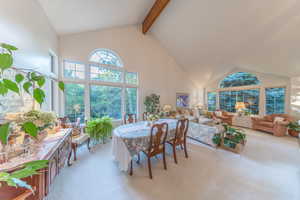 Dining room featuring light colored carpet, high vaulted ceiling, and beamed ceiling