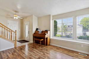 Entryway with laminate finished floors, fireplace, baseboards, and stairway