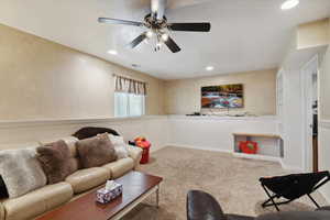 Living area with a ceiling fan, carpet floors, recessed lighting, and wainscoting