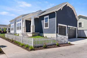 View of front facade featuring covered porch, stucco siding, driveway, an attached garage, and a fenced front yard