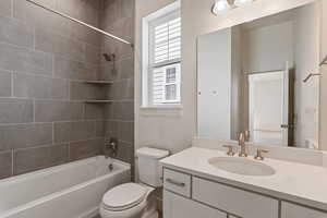 Full bath with toilet, plenty of natural light, vanity, and shower / washtub combination