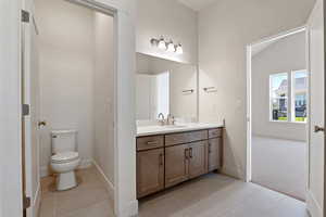Bathroom featuring tile patterned floors, vanity, toilet, and baseboards