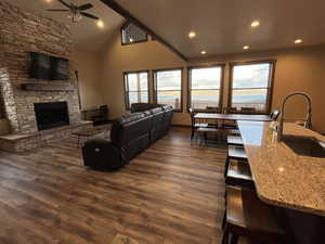 Living room featuring ceiling fan, healthy amount of natural light, a stone fireplace, dark wood-style floors, and recessed lighting