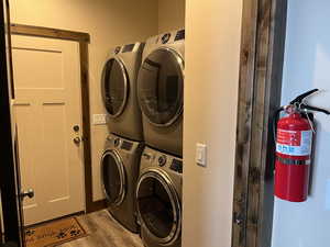 Laundry area featuring stacked washing machine and dryer and wood finished floors