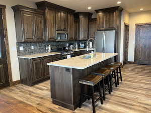 Kitchen featuring appliances with stainless steel finishes, a sink, light wood finished floors, baseboards, and recessed lighting