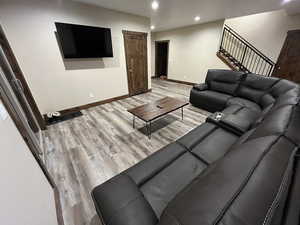 Living area with baseboards, recessed lighting, wood finished floors, and stairway