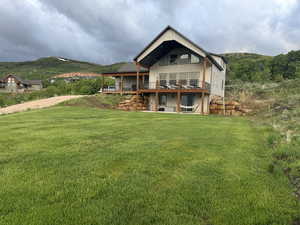 Back of property with a deck with mountain view and a yard