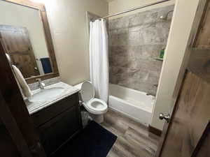 Bathroom featuring wood finished floors, vanity, toilet, and shower / bath combo with shower curtain