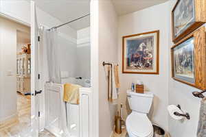 Bathroom with toilet and shower / tub combo with curtain