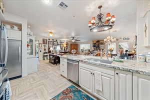 Kitchen featuring appliances with stainless steel finishes, a chandelier, a ceiling fan, and white cabinetry