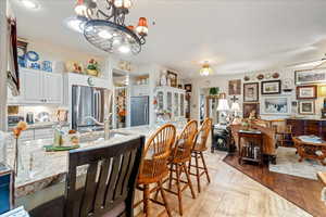 Kitchen with freestanding refrigerator, white cabinets, a chandelier, and light stone countertops