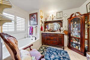 Bathroom featuring vanity, a bath, and tile patterned flooring