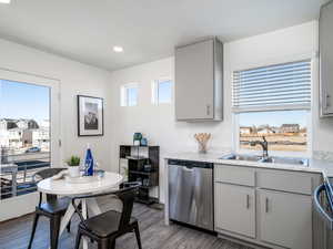Kitchen with dishwasher, light countertops, laminate wood floors, gray cabinetry, and recessed lighting