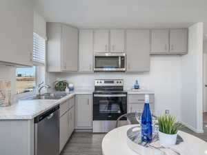 Kitchen with stainless steel appliances, light countertops, gray cabinets, and laminate wood floors