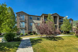 View of front of property featuring stone siding, a front lawn, and stucco siding