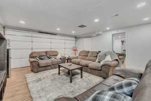 Living area featuring light wood finished floors, recessed lighting, and a garage
