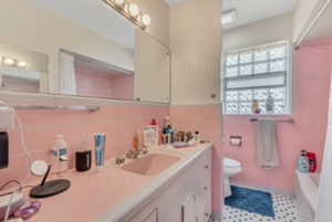 Bathroom featuring double vanity, toilet, tile walls, and shower / bathtub combination with curtain