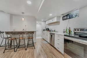 Kitchen featuring appliances with stainless steel finishes, white cabinets, light wood-style flooring, light countertops, and recessed lighting
