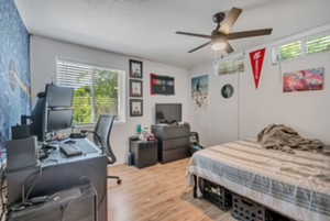 Bedroom featuring multiple windows, wood finished floors, a desk, and a ceiling fan