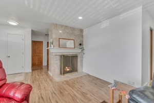 Living room with wood finished floors, a fireplace, and recessed lighting