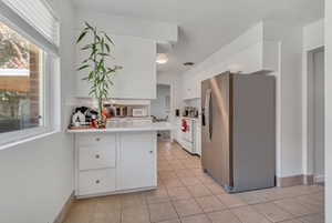 Kitchen with stainless steel fridge with ice dispenser, white cabinetry, plenty of natural light, and stove