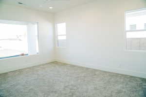 Carpeted spare room with a ceiling fan and baseboards