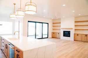 Kitchen featuring a sink, open shelves, recessed lighting, light wood-style floors, and stainless steel dishwasher