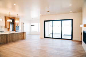 Unfurnished living room with a tiled fireplace, recessed lighting, light wood-style flooring, a sink, and ceiling fan