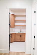Kitchen featuring a sink, open shelves, light countertops, and baseboards