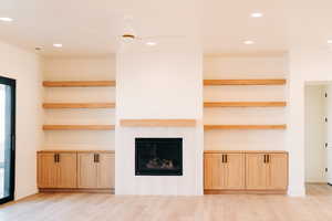 Unfurnished living room with light wood finished floors, recessed lighting, and a fireplace