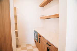 Bar with stainless steel microwave, light flooring, and baseboards