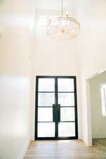 Detailed view of a chandelier, french doors, baseboards, and wood finished floors