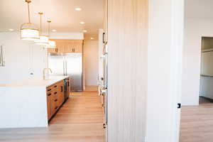 Kitchen featuring stainless steel built in refrigerator, light wood-style floors, light brown cabinets, oven, and recessed lighting