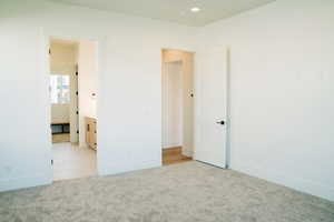 Unfurnished bedroom with light carpet, baseboards, and recessed lighting