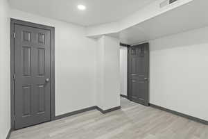 Empty room featuring light wood-style floors, baseboards, and recessed lighting