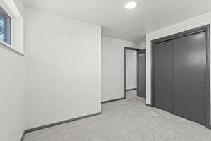 Unfurnished bedroom featuring light carpet, baseboards, and a closet