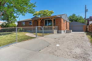 Ranch-style house with brick siding, a gate, a detached garage, covered porch, and an outbuilding