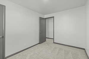 Spare room featuring light carpet and baseboards