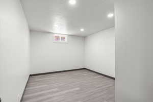 Unfurnished room featuring recessed lighting, wood finished floors, baseboards, and a textured ceiling