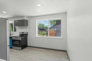 Kitchen with appliances with stainless steel finishes, healthy amount of natural light, decorative backsplash, light wood-style floors, and recessed lighting