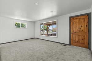 Carpeted spare room featuring baseboards