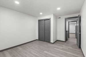 Unfurnished bedroom with light wood finished floors, baseboards, recessed lighting, and a closet