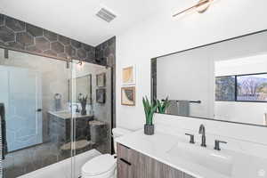 Bathroom featuring toilet, vanity, and a stall shower
