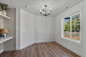 Unfurnished dining area with a chandelier, wood finished floors, and baseboards