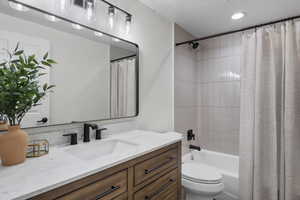 Bathroom featuring vanity, toilet, shower / bath combo, and recessed lighting
