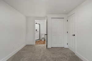 Unfurnished bedroom featuring carpet, baseboards, ensuite bathroom, and a closet