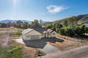View of front of house with driveway, an attached garage, a mountain view, and a view of countryside