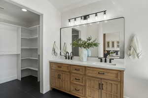 Full bathroom with double vanity, tile patterned flooring, and baseboards